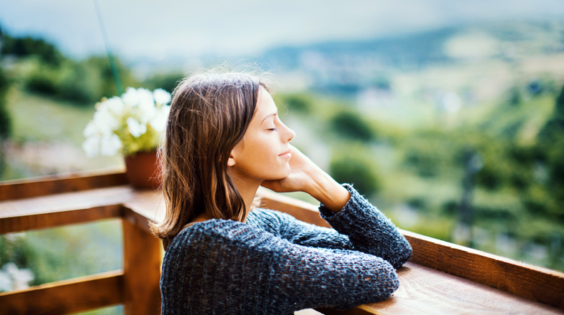 Young woman on a wellness retreat enjoying a fresh air on the mountain during summer morning